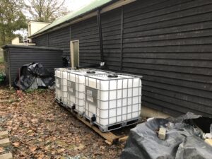 Three big plastic containers in temporary location to collect rain water